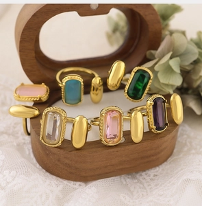 Gros plan de bagues en zircon émeraude et violette sur boîte bois et dentelle
