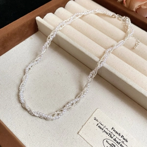 Detail of multi-strand woven necklace with faux pearls and silver textured chain