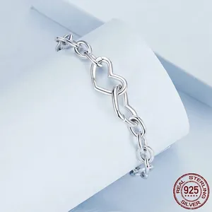 Minimalist S925 sterling silver interlocking heart bracelet on a white geometric display