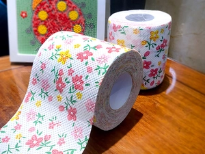 Detail of floral printed toilet paper roll with colorful flower patterns on wood table