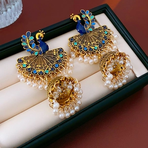 Detailed shot of peacock Jhumka earrings with blue enamel and white pearl tassels