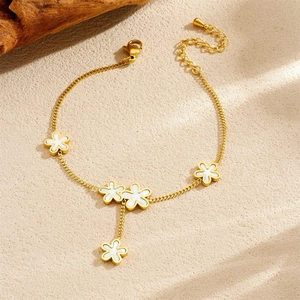 Close-up of golden four-leaf clover bracelet with white mother of pearl floral charms