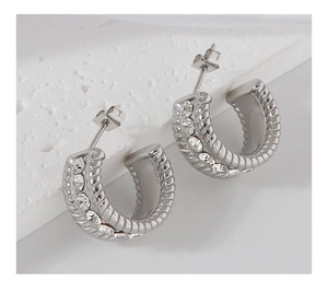 Macro shot of silver-colored twisted hoop earrings with sparkling cubic zirconia inlay