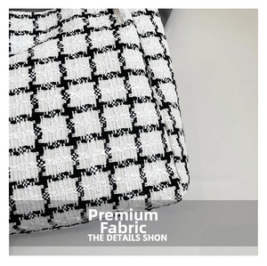 Close-up of premium black and white plaid tweed fabric showing detailed woven texture
