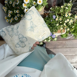 Detail of lace butterfly makeup bag with Sezakka label held in a lifestyle setting