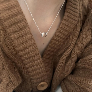 Close-up of minimalist S925 sterling silver ball pendant necklace on brown knit sweater