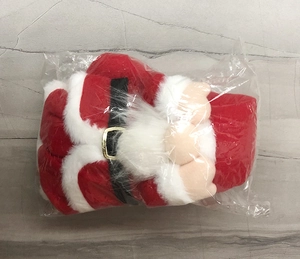 Detail of Christmas gnome plush doll in packaging showing red fabric and belt texture