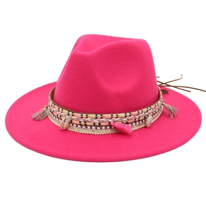 Detail of rose red fedora hat with bohemian braided band, shells and colorful tassels