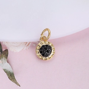 Macro shot of gold round pendant with black micro-stones and beaded texture edges