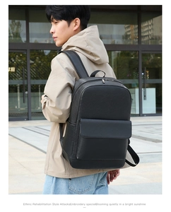 Man wearing large black leather business backpack outdoors with a modern background
