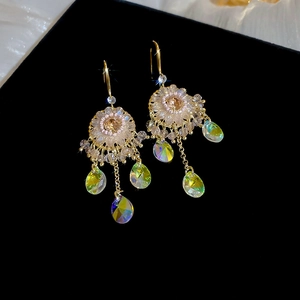 Macro shot of bohemian gold tassel earrings with iridescent crystal water drops and floral details