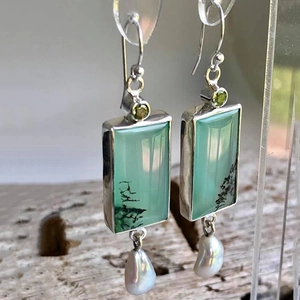 Retro geometric earrings with green stones and baroque pearl drops on wooden background