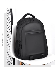 Detail of waterproof black business backpack with front zipper and top handle on a chair