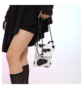 Close-up of quilted cow print crossbody bag with rope strap and Fashion label detail