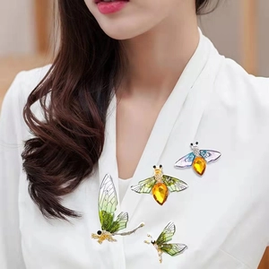 Detailed close-up of colorful enamel bee and dragonfly brooches with crystal inlay