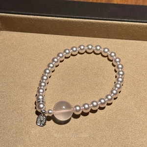 Détail du bracelet perlé avec perles roses et pendentif médaillon en argent gravé