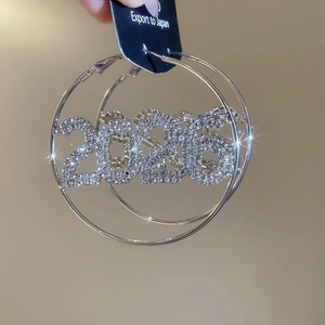 Dettaglio macro di orecchini a cerchio in argento con strass e design numero 2026