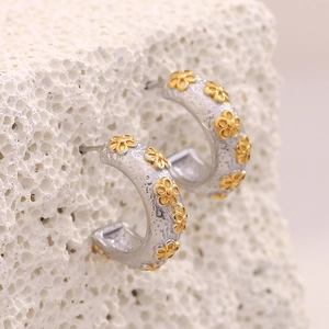 Two-tone 18K gold plated flower C-shaped hoop earrings on white stone display
