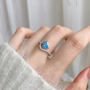 Macro shot of S925 silver ring featuring rectangular blue zircon with halo on finger