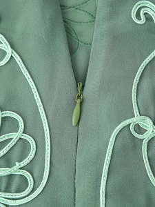 Gros plan sur un ensemble vert avec broderie florale et fermeture éclair invisible