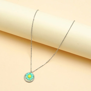 Detail of silver chain necklace with turquoise daisy pendant on a beige display stand