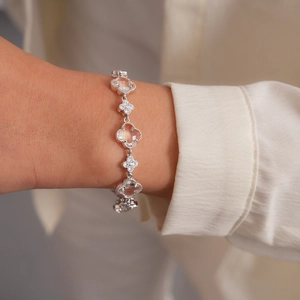 Détail d'un bracelet trèfle argenté orné de zircons brillants et bordures perlées