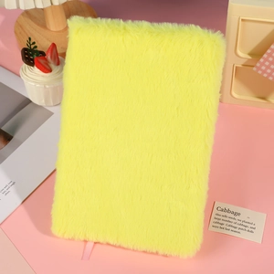 Detail of yellow plush notebook with soft faux fur texture and pink ribbon bookmark