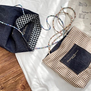 Detail of vintage denim and plaid canvas tote bags with colorful beaded shoulder straps