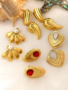 Close-up of vintage gold earrings with pearls and red gems on a marine theme background
