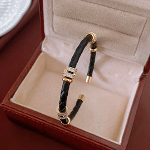 Détail d'un bracelet en cuir noir tressé avec fermoir doré serti de zircons blancs brillants