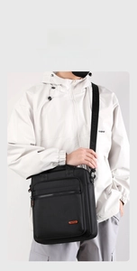 Detailed view of black multi-pocket crossbody messenger bag with adjustable strap and handle