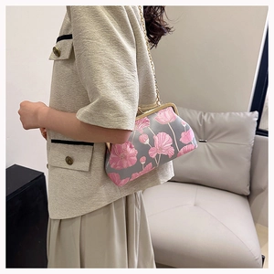 Elegante Damen-Muscheltasche mit rosa Blumenstickerei und goldener Kette am Modell