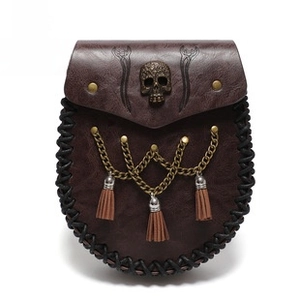Detail of steampunk waist bag with bronze skull emblem and leather fringe accents