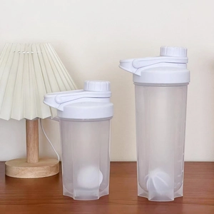 White protein shaker bottles with measuring scales and mixing balls on a wooden desk