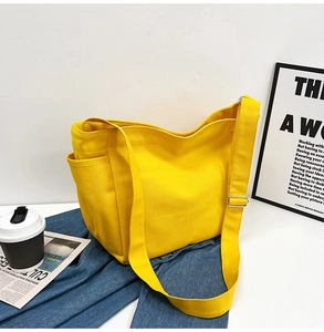 Detail view of bright yellow canvas tote bag featuring adjustable straps and side pocket