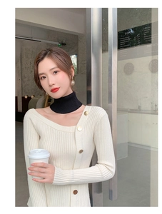 Detailed close-up of a black knitted turtleneck neck warmer styled with a white cardigan