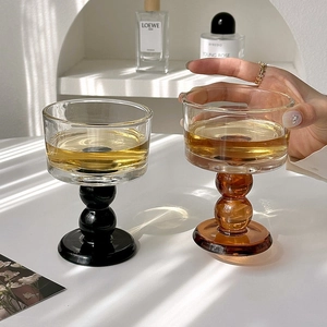 Vintage style wine glasses with black and amber stems on a table with natural light