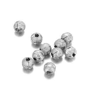 Frosted silver stainless steel beads with engraved star patterns on white background