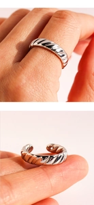 Detail of silver twisted wavy open ring showing adjustable band and textured metal finish