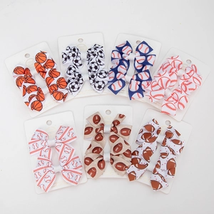 Detail view of handmade sports themed bow hair clips featuring soccer and baseball prints