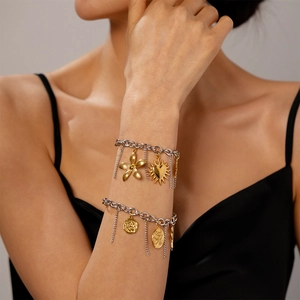 Detail of beach style stainless steel bracelets with flower and coin pendants on model wrist