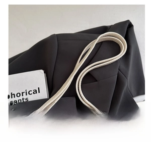 Close-up of adjustable cream leather shoulder strap with dark metal buckle and rivet details