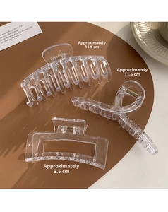 Detailed view of three transparent acrylic hair claws in various sizes on a brown leather base