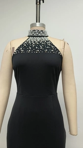 Detailed view of the black halter dress neckline featuring white pearls and rhinestones