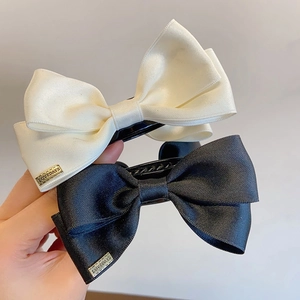 Elegant large satin bow hair claws in black and white with metal logo detail