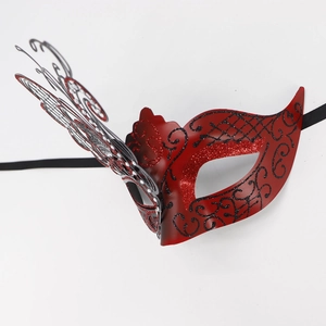 Detail of red Venetian masquerade mask with black glitter patterns and metal butterfly wing