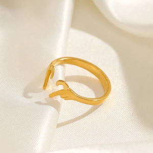 Golden hand-shaped open ring made of stainless steel on white silk background
