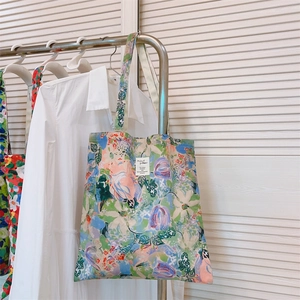 Close-up of abstract floral cotton tote bag with a small white label on a metal hanger