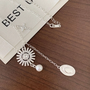 Close-up of S925 sterling silver asymmetrical chain with sun pendant and pearl detail