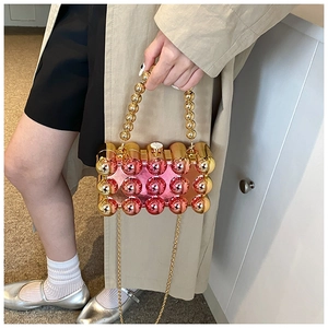 Detailed view of pink and gold beaded acrylic evening bag with metallic spheres and chain